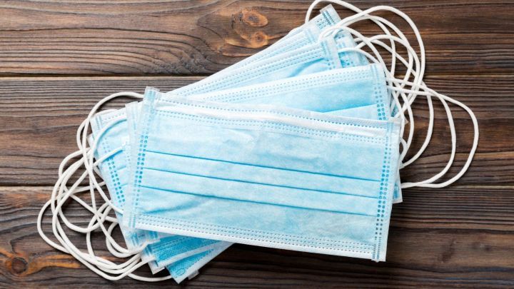 Mehrere medizinische Masken f&uuml;r Kinder liegen gestapelt auf einem Holzuntergrund, bereit zum Anpassen oder K&uuml;rzen.