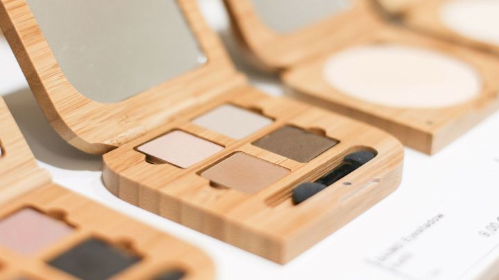 Ein elegantes, bambusgefasstes Make-up-Palette mit verschiedenen Lidschattenfarben liegt offen auf einem Tisch.