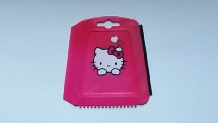 Ein rosa Eisschaber mit einem Hello-Kitty-Motiv liegt auf einem wei&szlig;en Hintergrund, bereit zum Schneiden oder Schaben.