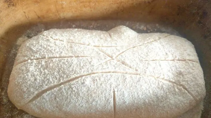 Das Brot in den R&ouml;mertopf legen, mit Mehl best&auml;uben oder K&ouml;rnern bestreuen. Nun kann in das Brot ein Muster geritzt werden, damit es nicht unkontrolliert rei&szlig;t. Wie ihr schneidet, ist dabei egal.