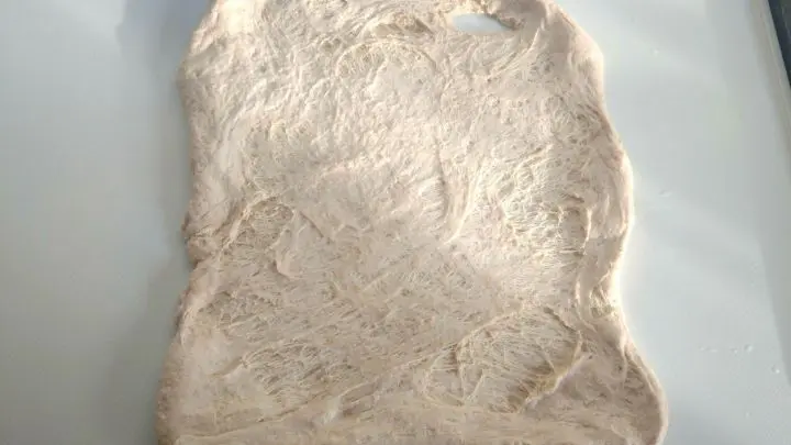 Um Brot zu falten muss als erstes die Teigkugel auseinander gezogen werden. So, dass eine Teigplatte entsteht.