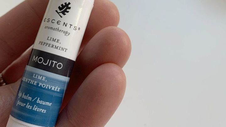 Ein Lippenbalsam wird in der Hand gehalten, um Risse an den Fingerkuppen zu behandeln. Im Hintergrund sind Lichter.