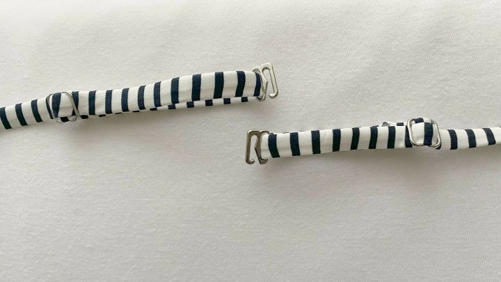 Zwei gestreifte BH-Tr&auml;ger liegen auf einem wei&szlig;en Untergrund, bereit, um an einem Sommertop befestigt zu werden.