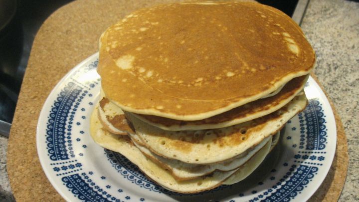 Auf einem blauen Teller liegen mehrere goldbraune Dinkel-Eierkuchen &uuml;bereinander, bereit zum Servieren.