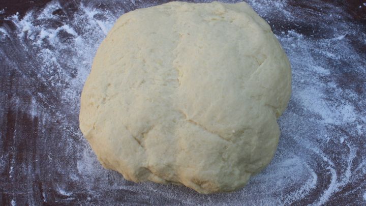 Ein runder Teigklumpen liegt auf einer bemehlten Fl&auml;che und wartet darauf, zu Maultaschen oder Schlutzkrapfen verarbeitet zu werden.