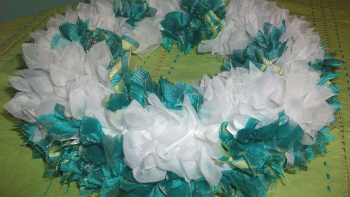 Ein Dekokranz aus Sp&uuml;lt&uuml;chern zeigt eine bunte Komposition aus wei&szlig;en und t&uuml;rkisfarbenen T&uuml;chern auf einem gr&uuml;nen Untergrund.