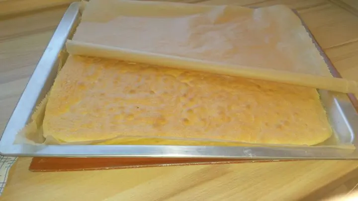 Die Biskuitrolle wird nach dem Backen von beiden Seiten mit Backpapier bedeckt und eingerollt. Dann muss sie ausk&uuml;hlen