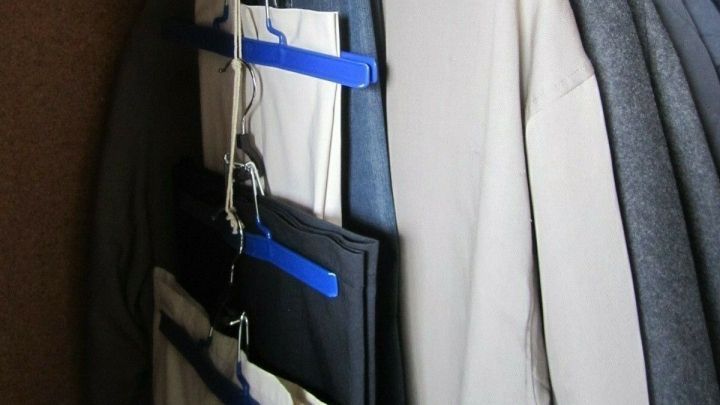 Im Kleiderschrank h&auml;ngen verschiedene Kleidungsst&uuml;cke an blauen Kleiderb&uuml;geln. Platz wird effektiv genutzt, um mehr Ordnung zu schaffen.
