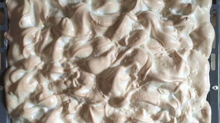 Ein Blech voller goldbrauner, luftiger Baisermasse ist auf einem Backblech zu sehen und wirkt frisch zubereitet.