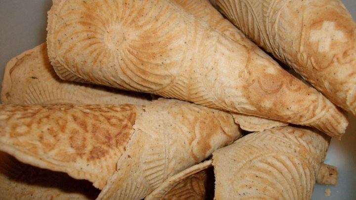 Kaffee-Zimt-Eiswaffelh&ouml;rnchen liegen &uuml;bereinander in einer Sch&uuml;ssel und zeigen ihre gemusterte Oberfl&auml;che.