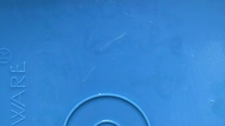 Eine blaue Plastikdose liegt auf einer Oberfl&auml;che, sichtbar sind eine klare Beschriftung und das Markenlogo.