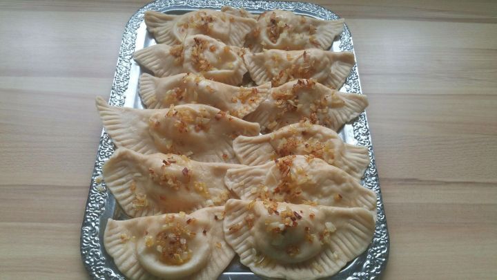 Piroggen mit Kartoffel-Zwiebel-Quark-F&uuml;llung liegen appetitlich auf einer silbernen Platte und warten auf den Verzehr.