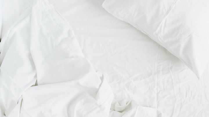 Ein ungemachtes Bett mit wei&szlig;en Laken und einem Kopfkissen wirkt unordentlich und ben&ouml;tigt Pflege, um l&auml;nger frisch zu bleiben.