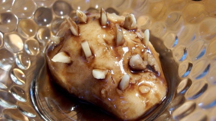 Ein niedlicher Birnenigel liegt auf einem dekorativen Glasplattenuntergrund, umgeben von kleinen Stiften oder N&uuml;ssen, die ihn verzieren.