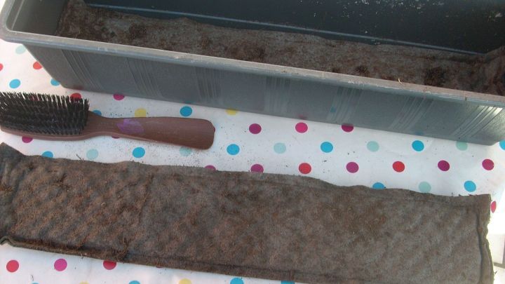 Eine Drainagematte liegt neben einem leeren Blumenkasten, w&auml;hrend eine B&uuml;rste f&uuml;r die Reinigung bereitliegt.