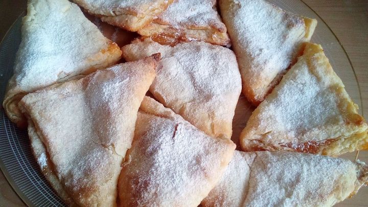 Quark-Kissen liegen auf einem Teller, puderzuckerbest&auml;ubt, bereit zum Genie&szlig;en in einer gem&uuml;tlichen K&uuml;che.