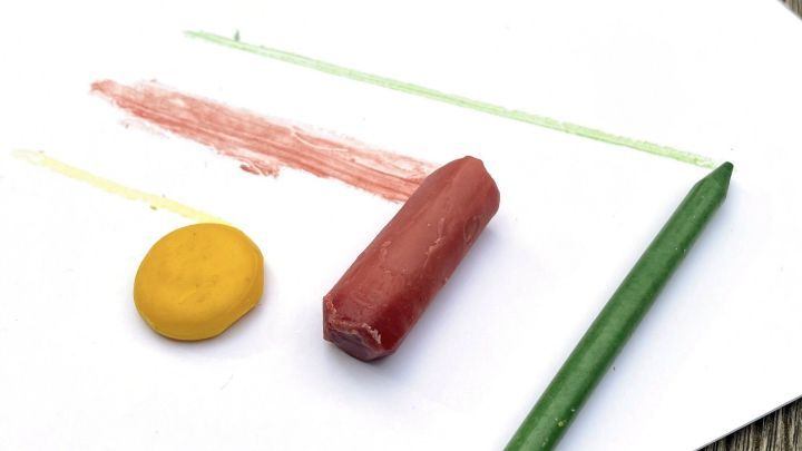 Auf einem wei&szlig;en Blatt Papier liegen ungiftige Wachsmalstifte aus Bienenwachs und zeigen bunte Farbstreifen.