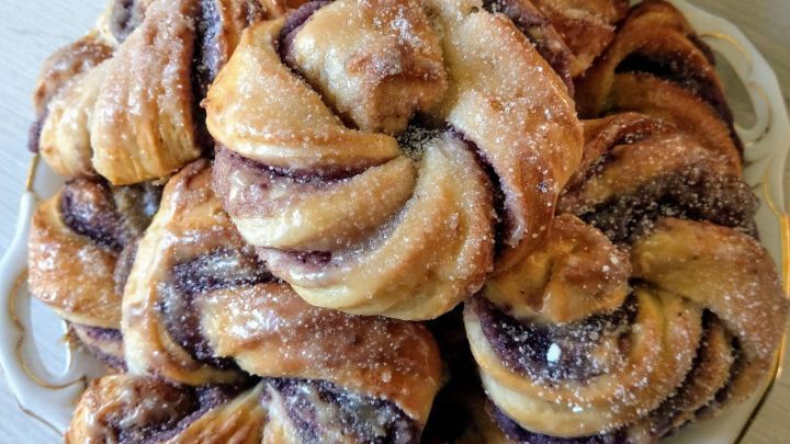 Geschichtete Schwedische Blaubeerwirbel liegen verf&uuml;hrerisch auf einem Teller und sind mit Zucker bestreut.