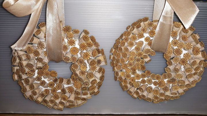 Zwei runde Deko-Wrappen aus verbl&uuml;hten Mohnblumen liegen elegant an einer Wand und sind mit einem Satinband geschm&uuml;ckt.