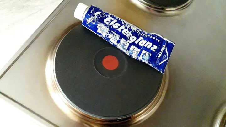 Eine Tube Edelstahlreiniger liegt auf einer Kochplatte, w&auml;hrend der gl&auml;nzende Edelstahl im Hintergrund sichtbar ist.