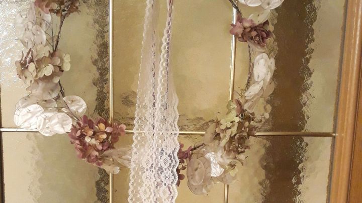 Ein Herbstkranz aus Naturmaterialien h&auml;ngt dekorativ an einer gegen&uuml;berliegenden Glast&uuml;r und strahlt rustikalen Charme aus.