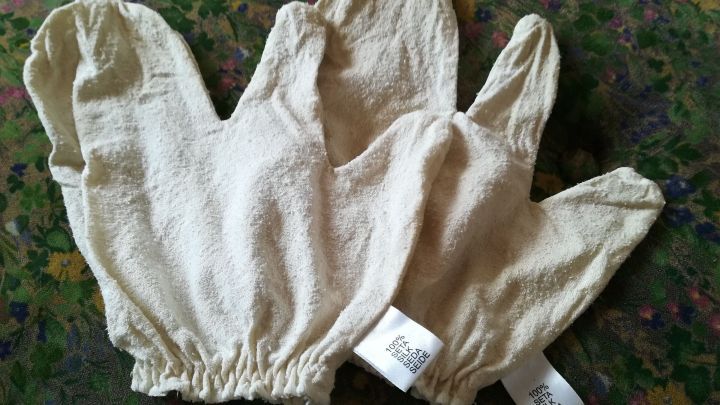 Seidenhandschuhe liegen auf einem bunten Stoff, bereit f&uuml;r eine Massage zur Anregung des Stoffwechsels.