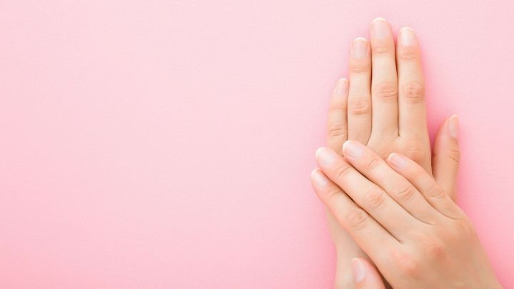 Kurze Fingern&auml;gel liegen nebeneinander auf einem rosa Hintergrund, bereit f&uuml;r das Auftragen von Nagellack mit Lackierhilfe.