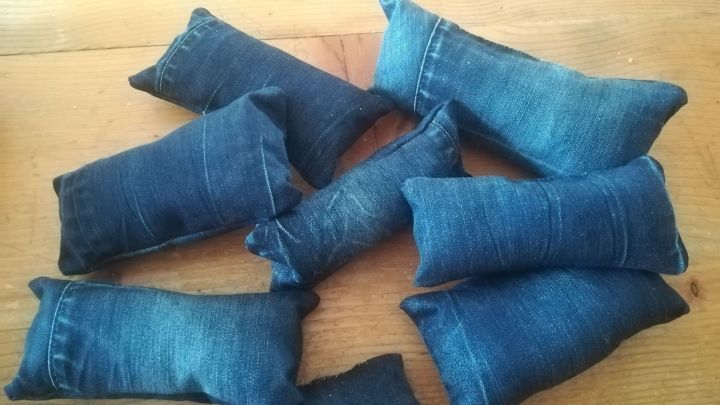 Mehrere handgemachte Baldrians&auml;ckchen aus Jeansstoff liegen auf einem Holztisch, bereit zum Spielen f&uuml;r Katzen.