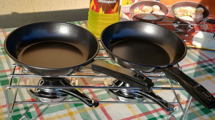 Eine doppelte Pfanne steht auf einem Gaskocher, bereit zum Kochen ohne Strom, umgeben von einer karierten Tischdecke.