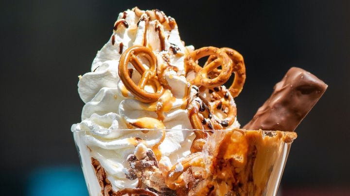 Ein Dekorationsbecher mit Sahne, Schokolade und Brezeln steht vor uns. Genie&szlig;en Sie ein kalorienreiches Dessert!