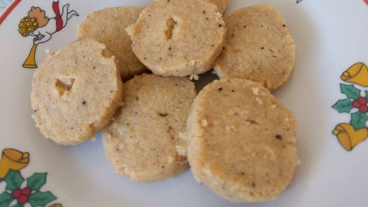 Runde Heidesand-Pl&auml;tzchen liegen auf einem Teller, umgeben von einer festlichen Weihnachtsdekoration, bereit zum Genie&szlig;en.