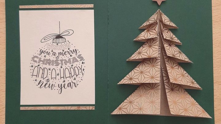 Eine gefaltete Weihnachtskarte zeigt einen dreidimensionalen Tannenbaum aus braunem Papier und einen Gru&szlig;text.
