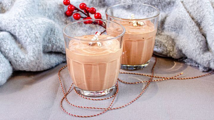 Zwei Gl&auml;ser mit veganer Mousse au Chocolat stehen auf einem grauen Tisch, umgeben von einem flauschigen Tuch und roten Beeren.
