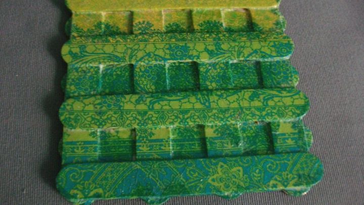 Farbige Untersetzer aus Mundspateln liegen auf einem dunklen Untergrund und zeigen ein bl&uuml;hendes, gemustertes Design.