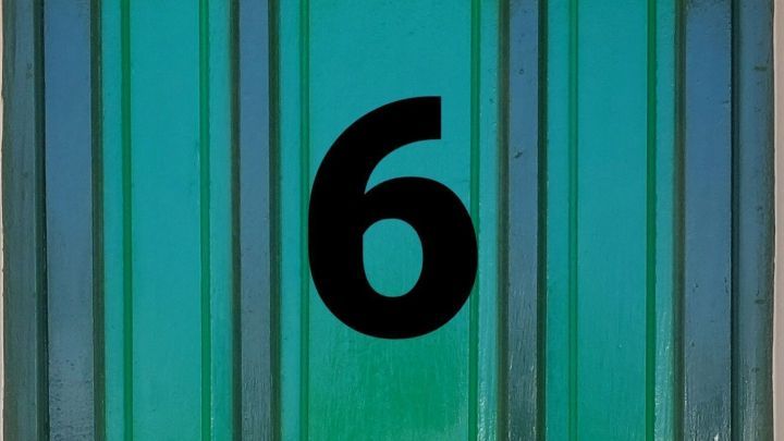 Ein gr&uuml;nes T&uuml;rblatt zeigt die Zahl 6, bereit f&uuml;r eine Entdeckung hinter einem Adventskalender, in einem simplen Umfeld.