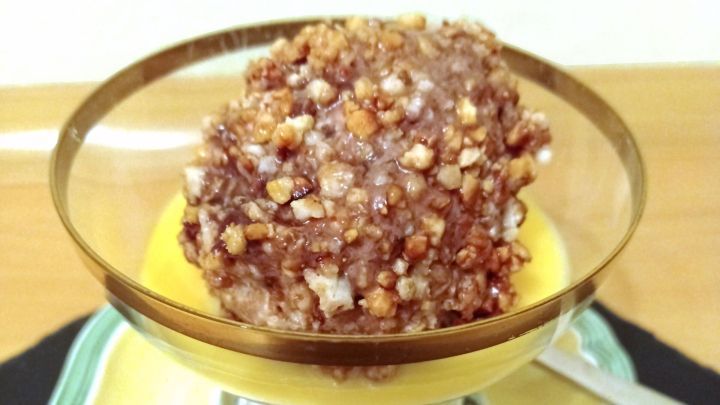 Eine Eispraline mit knackiger Nusskruste schwimmt in einem Eierlik&ouml;rbad, serviert in einer eleganten Glasschale.