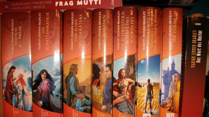 Sieben B&uuml;cher des Darkover-Roman-Zyklus stehen nebeneinander im Regal, jede mit einer fantasievollen Illustration.