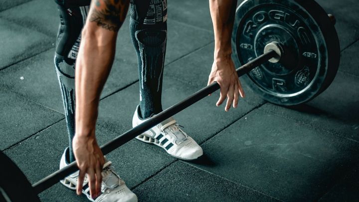 Ein Athlet hebt eine Langhantel, um Verletzungen wie Blasen w&auml;hrend des Sports zu vermeiden, in einem Fitnessstudio.