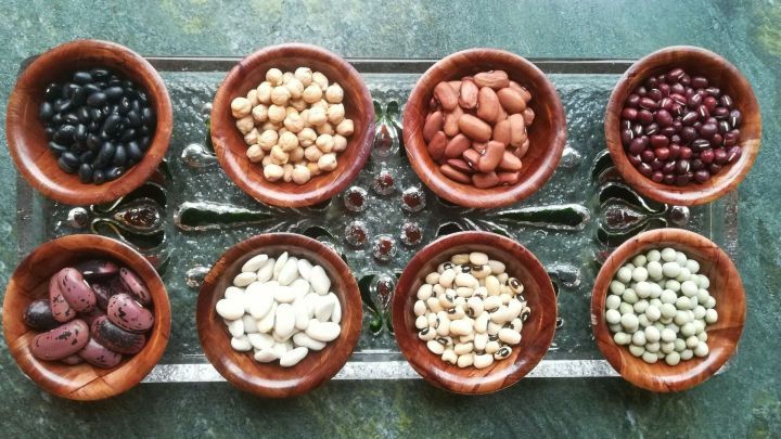 Bunte Schalen mit verschiedenen H&uuml;lsenfr&uuml;chten sind auf einem dekorativen Teller angeordnet, bereit zum Kochen.