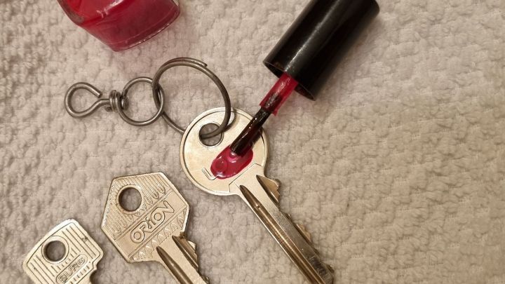 Ein roter Nagellack wird auf den Schl&uuml;ssel auf einem weichen, hellen Untergrund aufgetragen, um Schl&uuml;ssel zu kennzeichnen.