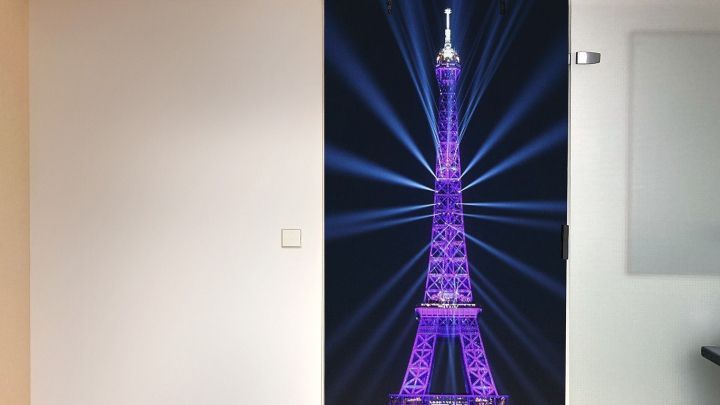 Eine Verdunkelungst&uuml;r auf Rollen zeigt den leuchtend lila Eiffelturm, der in einem modernen Raum als Dekoration dient.