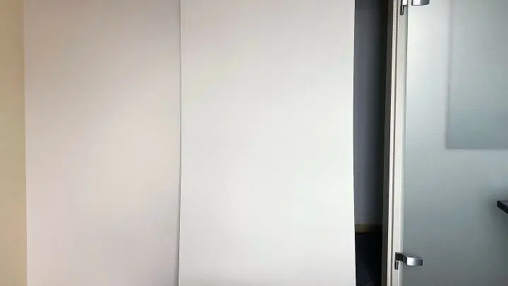Die weiße Rückseite der ausgehängten und nur angelehnten Schwebetür. Man kann gut erkennen, wie sie sich leicht durchbiegt.
