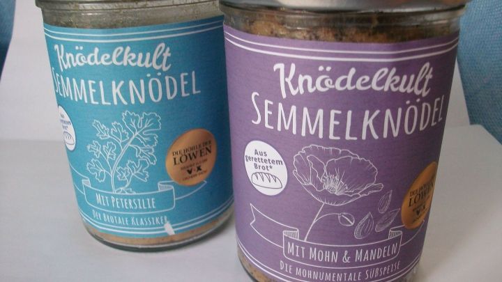 Zwei Gl&auml;ser Kn&ouml;delmischung stehen nebeneinander, eines mit Petersilie und das andere mit Mohn und Mandeln, auf wei&szlig;em Hintergrund.