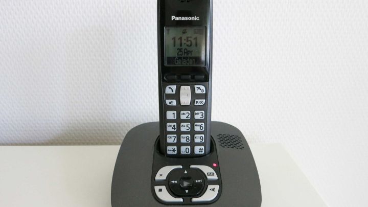 Ein schnurloses Telefon steht auf einer Basisstation und zeigt die Uhrzeit an, bereit f&uuml;r kostenloses Telefonieren.