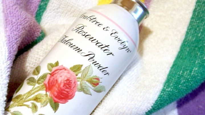 Eine Dose Crabtree & Evelyn Rosewater Talcum Powder liegt auf einem bunten Handtuch. Die Dose zeigt eine Rose.