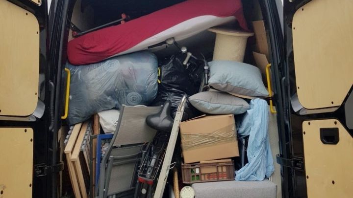 Ein umgepackter Transporter steht offen und zeigt eine volle Ladung von M&ouml;beln und Kartons, bereit f&uuml;r die erste eigene Wohnung.