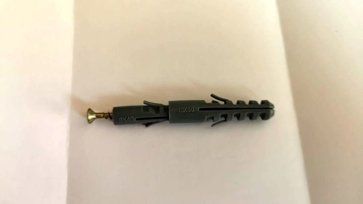 Ein D&uuml;bel liegt auf einer wei&szlig;en Oberfl&auml;che, bereit zum Befestigen in weichen Materialien, um Stabilit&auml;t zu bieten.