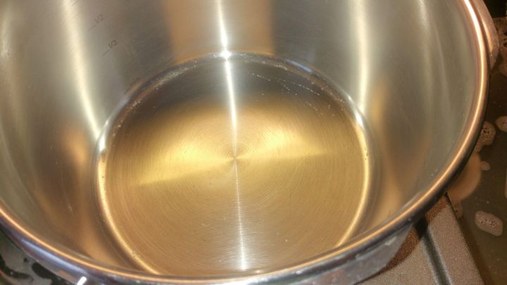 Ein gl&auml;nzender Edelstahltopf steht auf einem Herd und reflektiert das Licht, bereit zum Reinigen.