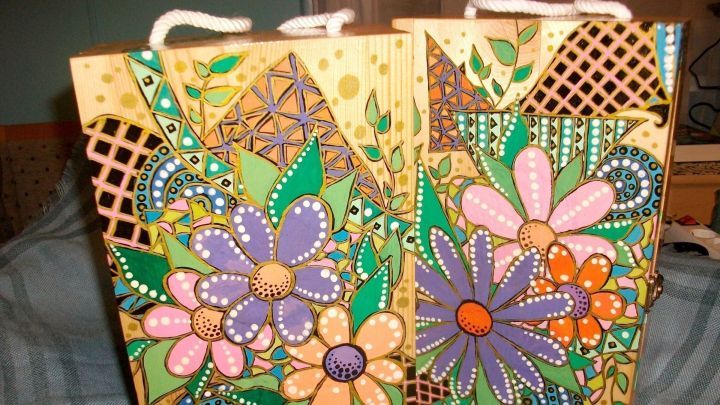 Bunte Holz-Weingeschenkkisten mit floralen Mustern stehen dekorativ auf einem Tisch in einer gem&uuml;tlichen Umgebung.