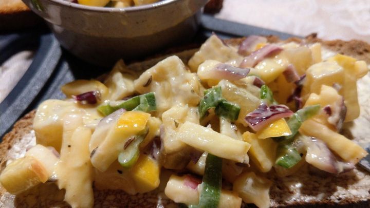 Auf einem St&uuml;ck Brot liegt ein Handk&auml;se-Tatar mit bunten W&uuml;rfeln, umgeben von einem kleinen Sch&auml;lchen mit der restlichen Mischung.